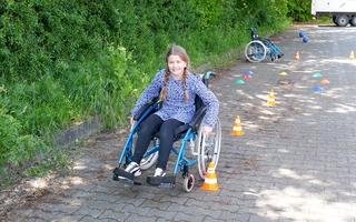 Ein Mädchen in einem Rollstuhl rollt durch einen Parkour.