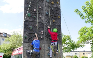 Zwei Jungs klettern eine mobile Kletterwand hinauf.