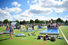 Kinder spielen auf einer Wiese mit vielen Mitmachangeboten.