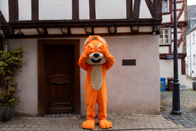 Das Maskottchen der hessischen Turnjugend steht vor einem Haus in Limburg