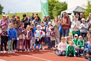 Viele Teilnehmende stehen um einen Sportplatz herum.