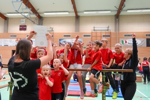 Eine Gruppe Kinder freut sich mit ihren Trainerinnen über eine Auszeichnung.