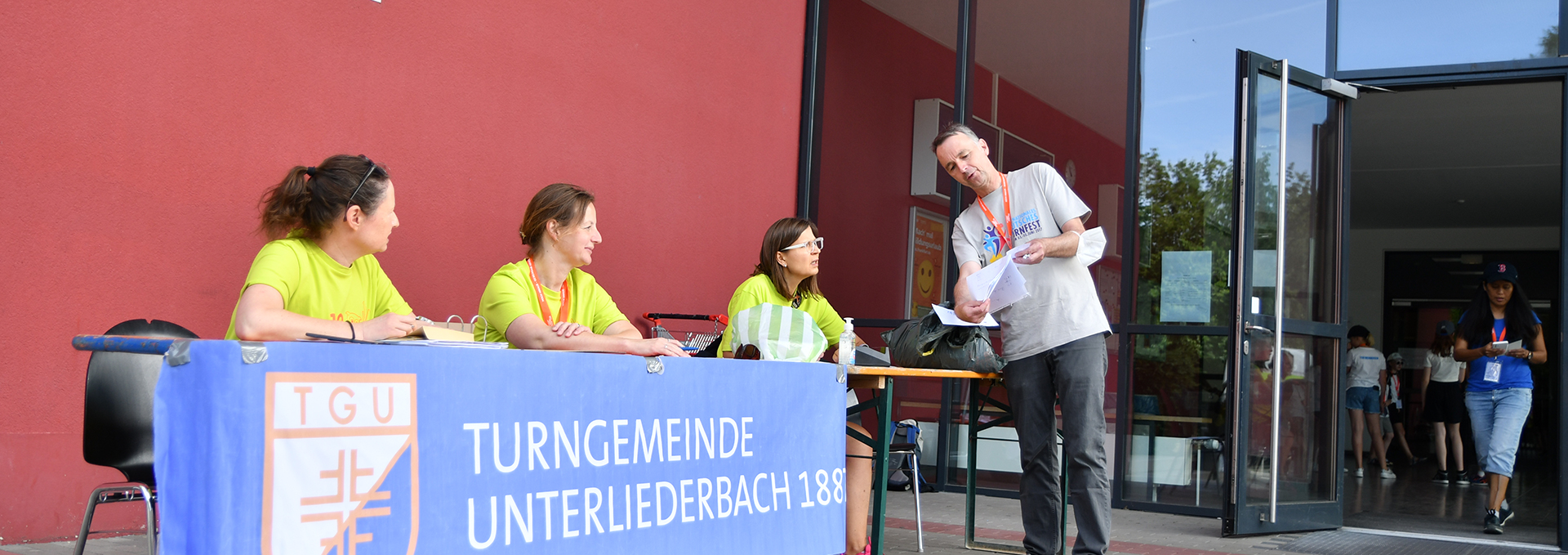 Drei Frauen sitzen an einem Tisch und helfen einem Mann weiter.