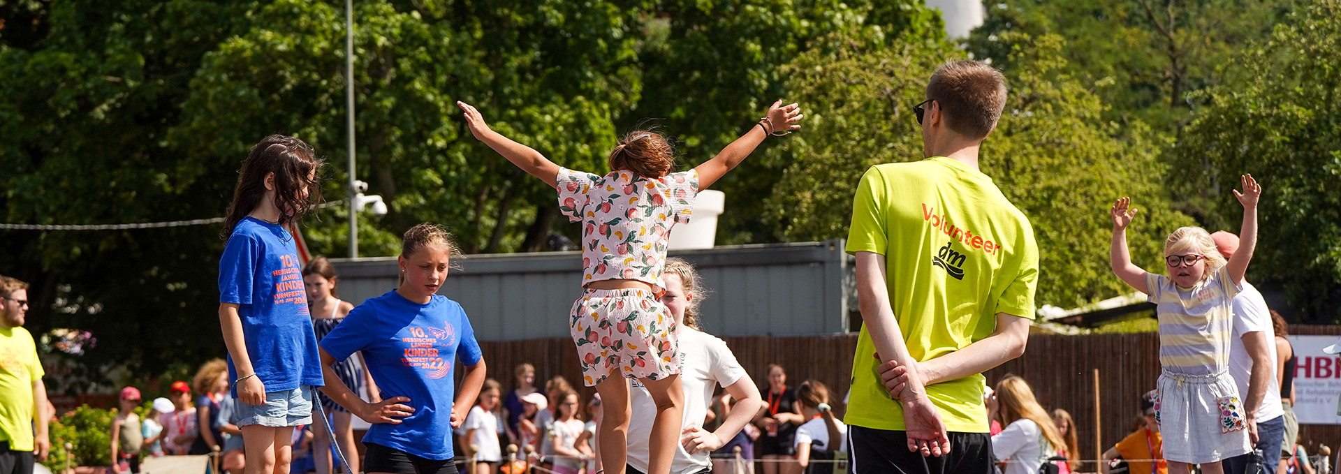 Ein Mädchen springt auf einem Trampolin und wird dabei von einem Volunteer betreut.