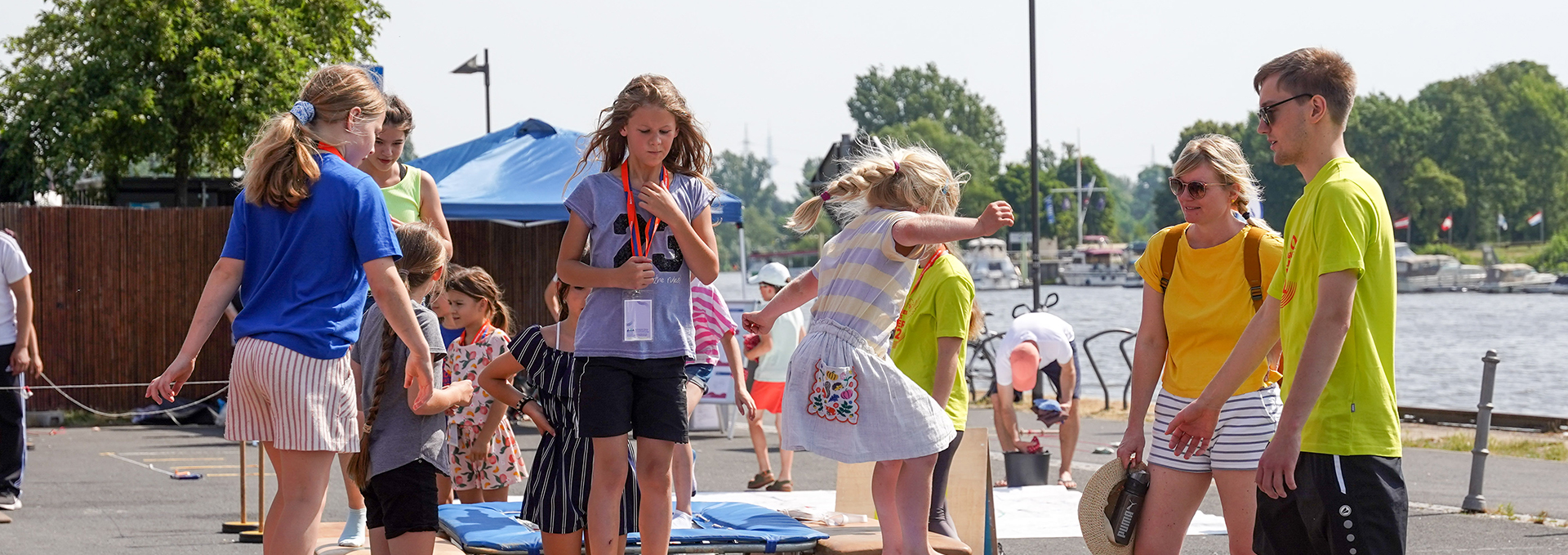 Ein Mädchen springt auf einem kleinen Trampolin, drumherum stehen mehrere Personen.