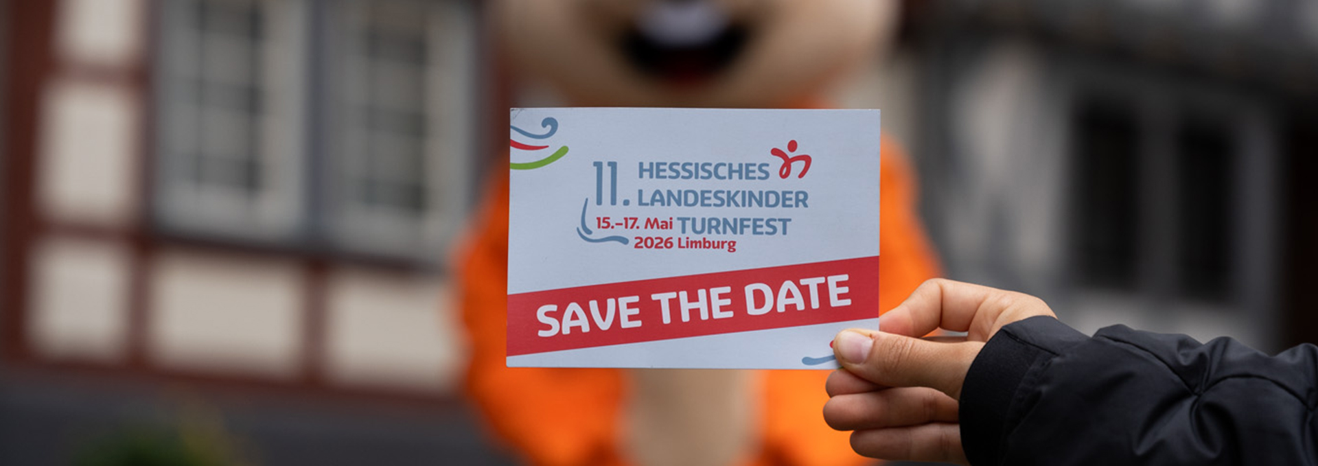 Eine Hand hält die Postkarte vom 11. Landeskinderturnfest ins Bild.