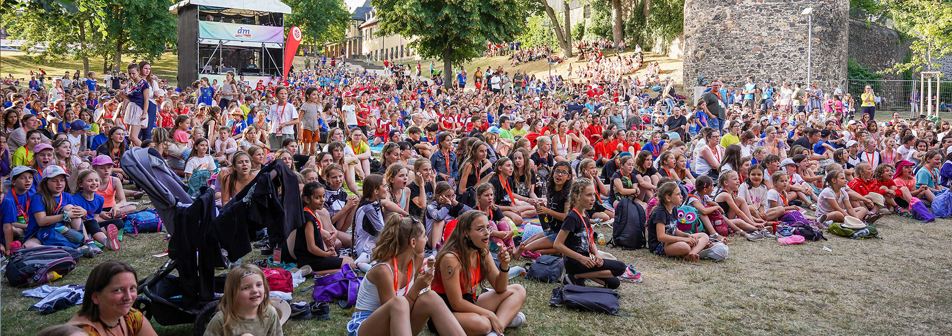 Viele Menschen sitzen auf einer Wiese.