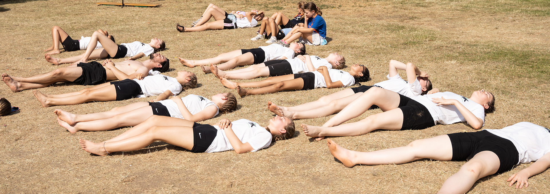 Eine Gruppe von Personen liegt entspannt auf einer Rasenfläche.