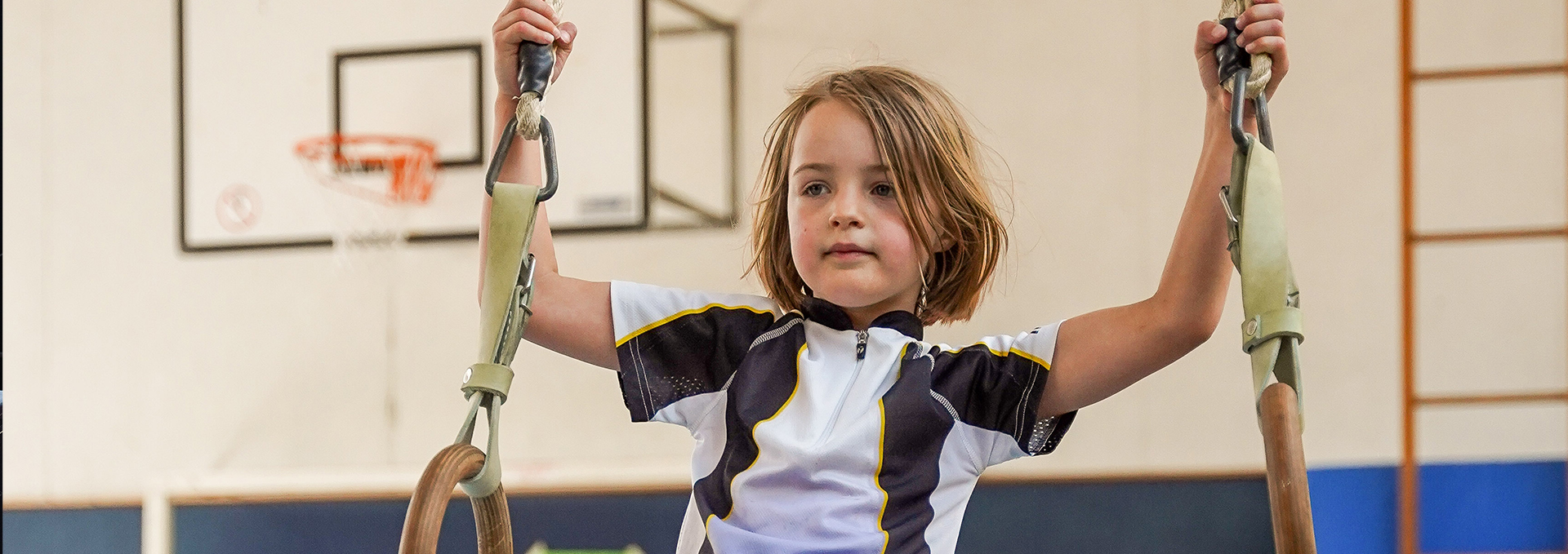 Ein Kind schwingt auf einer Schaukel in einer Turnhalle.