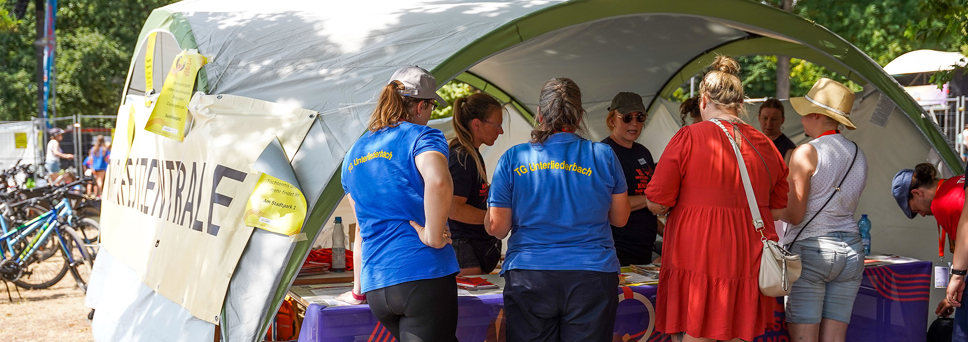 Mehrere Personen stehen an einer Turnfestzentrale.