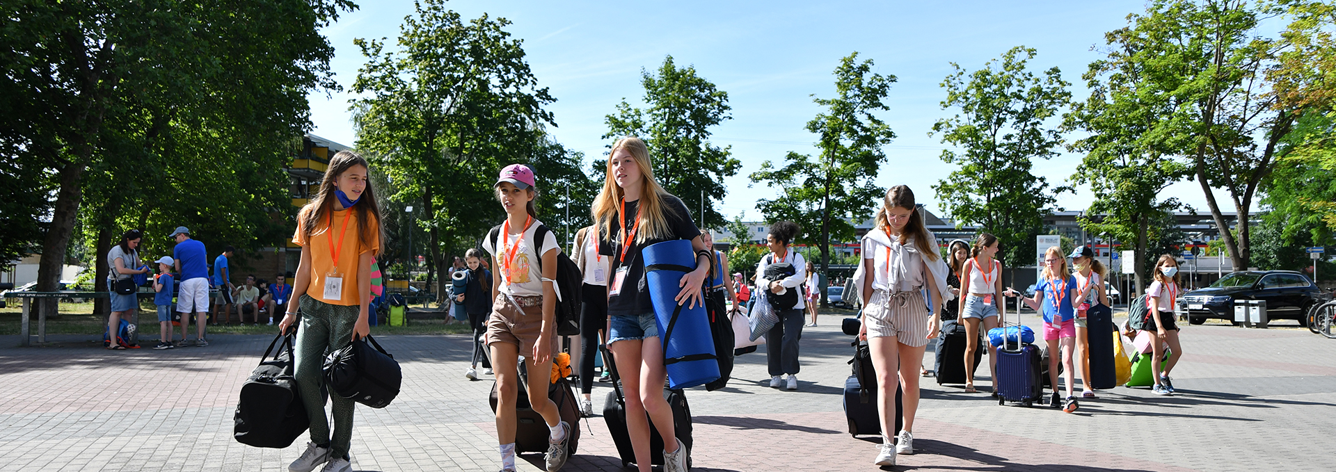 Mehrere Kinder reisen mit Gepäck beim Turnfest an.