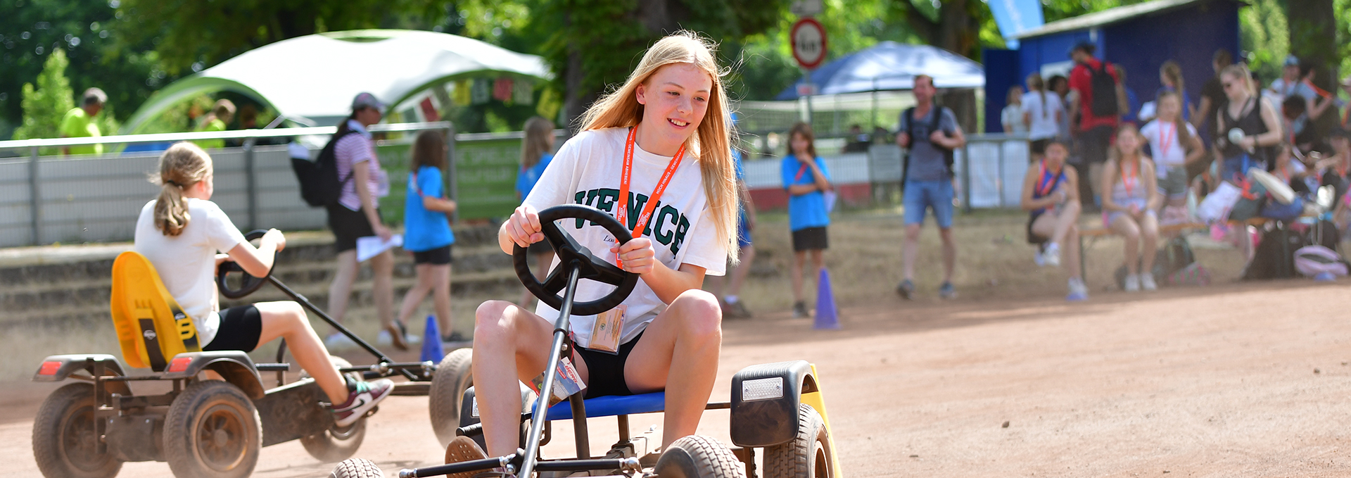 Ein Mädchen fährt mit einen Dreirad durch einen Parkour.