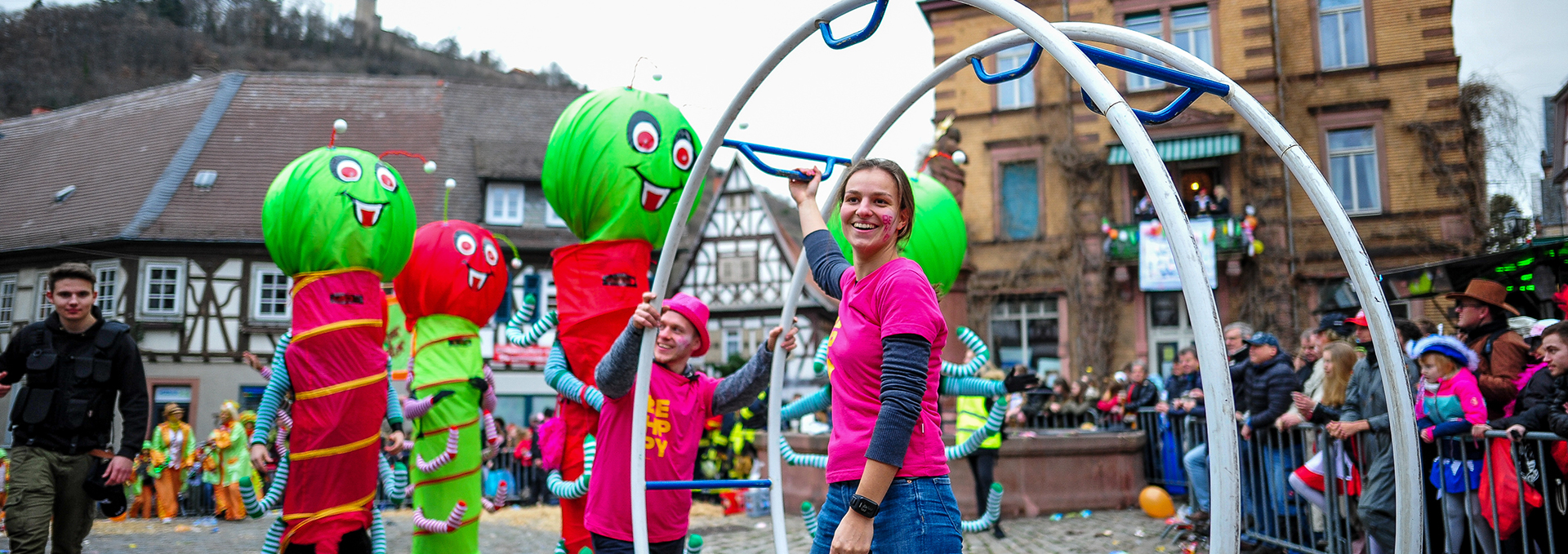 Ein bunter Festumzug in einer Altstadt mit vielen Personen.