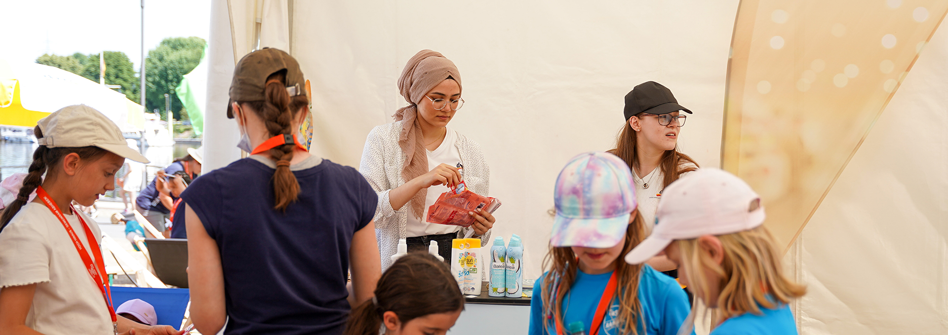 Eine Frau betreut an einem Stand auf der Turnfestmeile verschiedene Personen.