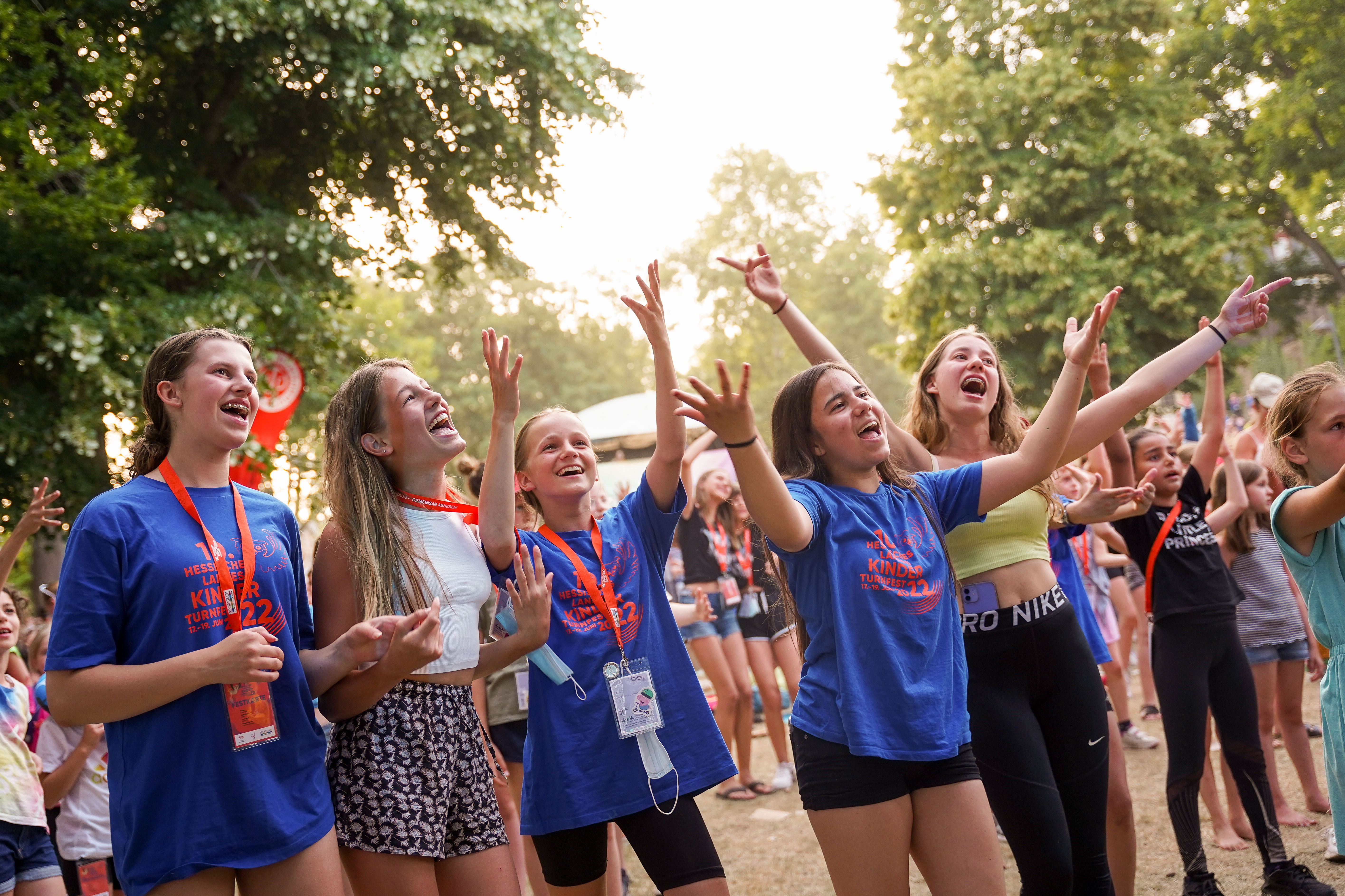 Mehrere Menschen feiern und singen auf einer großen Wiese.