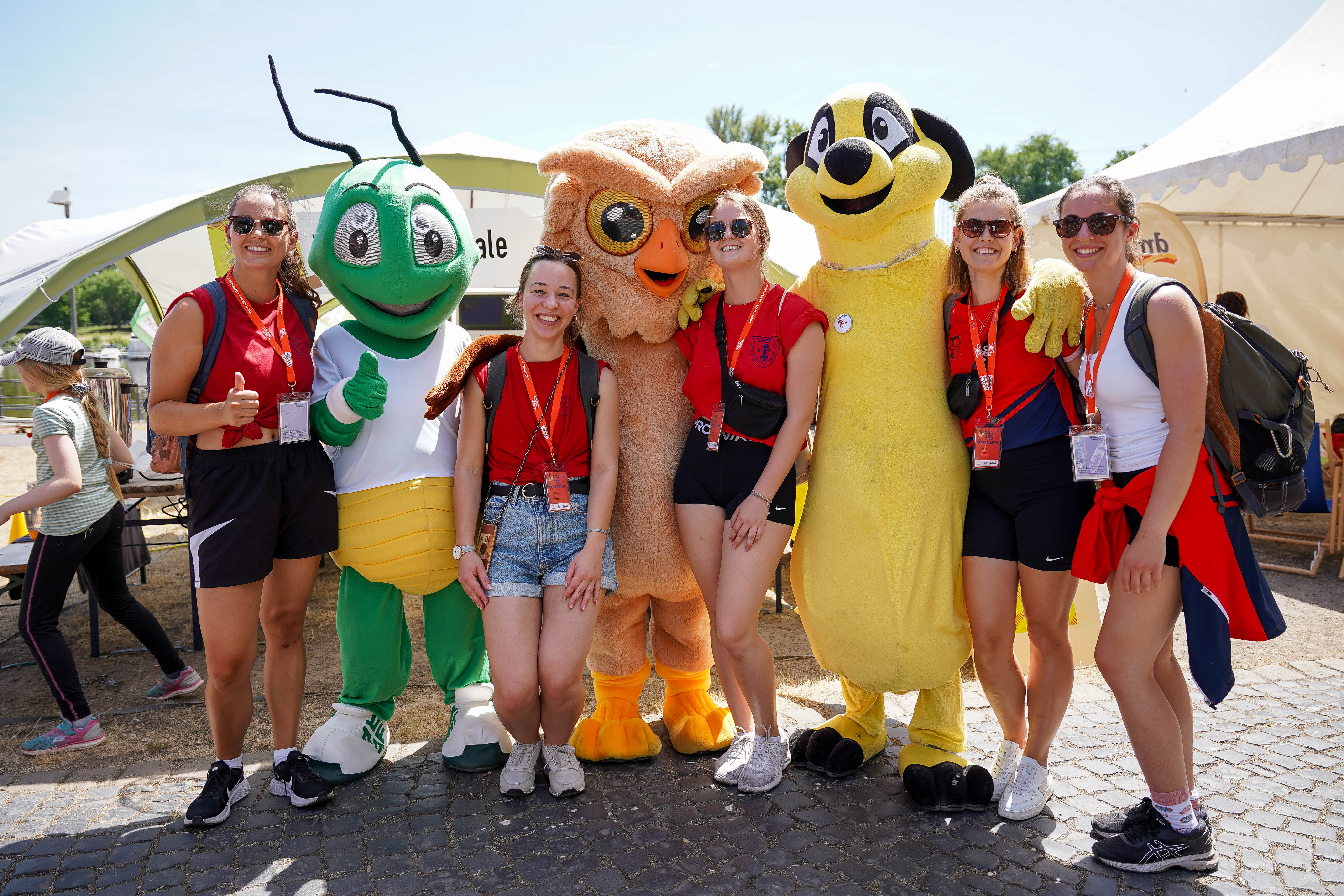 Eine Gruppe von Frauen posieren für ein Foto mit dem Turnfest-Maskottchen.