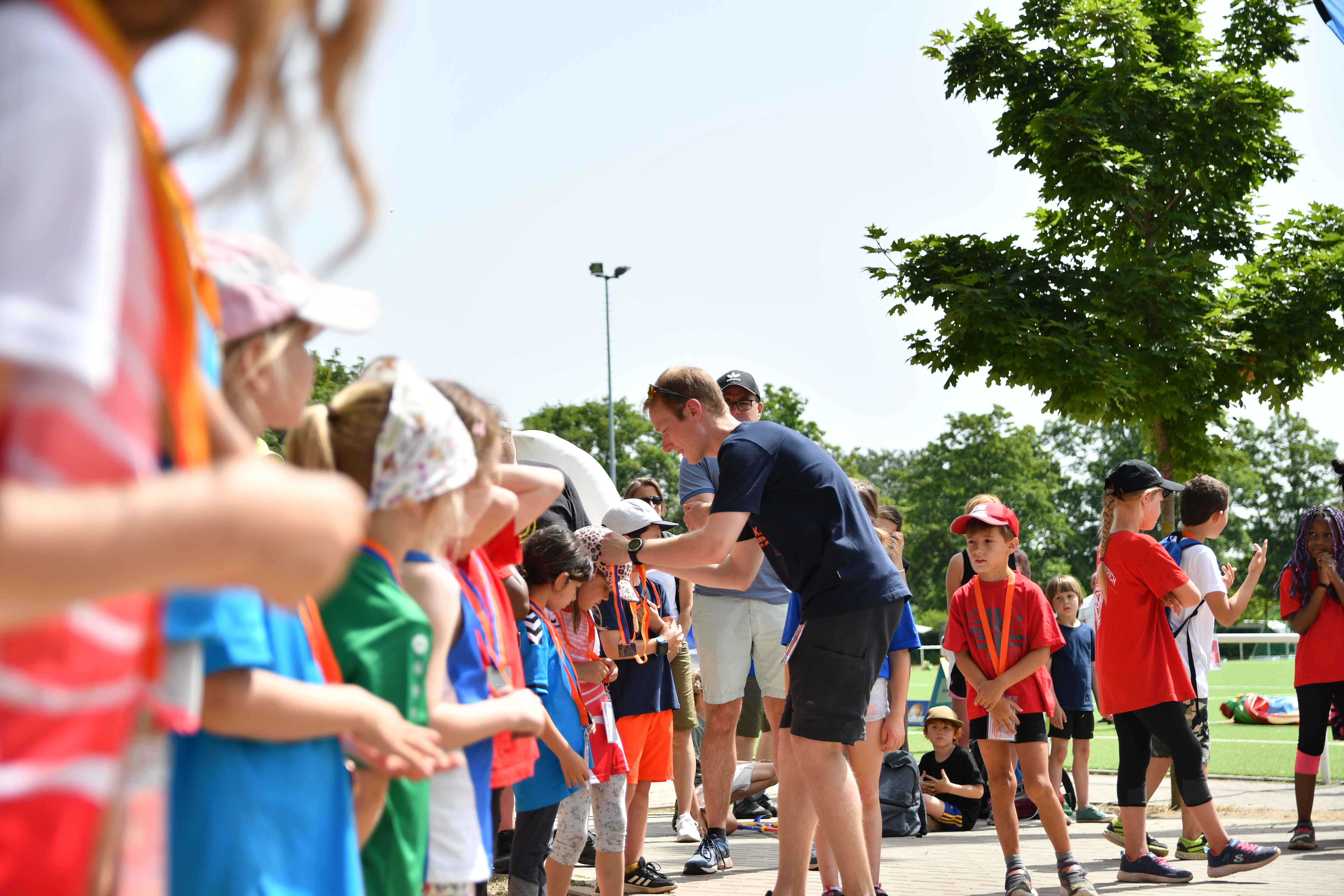 Ein Mann hängt Kindern Medaillen um. 